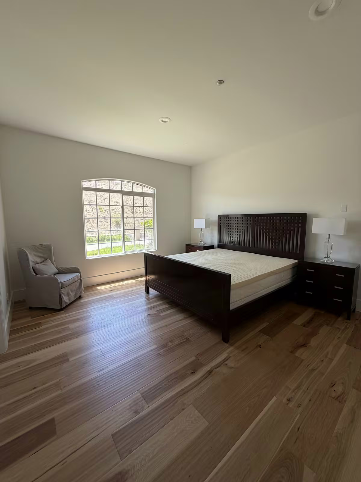Bedroom with bed and armchair after painting, arched window