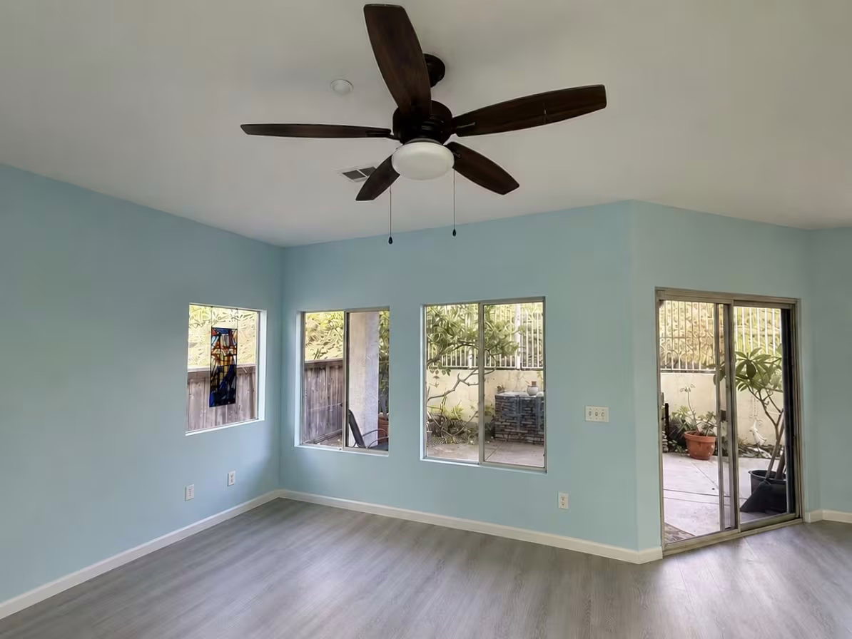 Living room with ceiling fan and teal walls after painting
